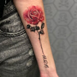 Ein Tattoo einer Rose am Unterarm mit einem Datum