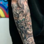 Arm Tattoo mit chinesischem Drachen in grau mit hellblauen Augen