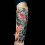 Schwarzer Koi mit orangener Blüte als Unterarm Tattoo