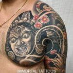 Brust- und Oberarm Tattoo, als Motiv eine böse Hindu Gottheit mit Blüten